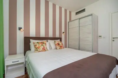 a bedroom with a bed and a striped wall at Apartments Fortunella in Petrovac na Moru