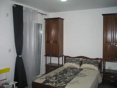 a bedroom with a bed and a wooden cabinet at Guest House Dena in Dobra Voda