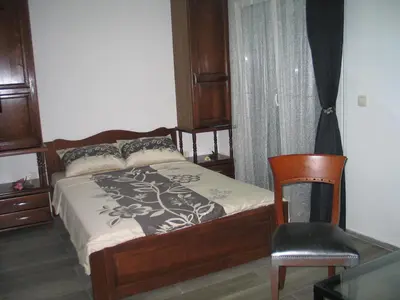 a bedroom with a bed and a chair and a window at Guest House Dena in Dobra Voda