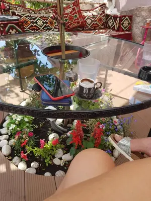 a table with a glass table with flowers and a cup of coffee at Guest House Dena in Dobra Voda