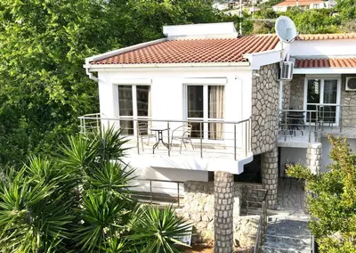a white house with a balcony and trees at Villa Radis in Dobra Voda