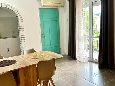 a dining room with a table and a green door at Villa Radis in Dobra Voda