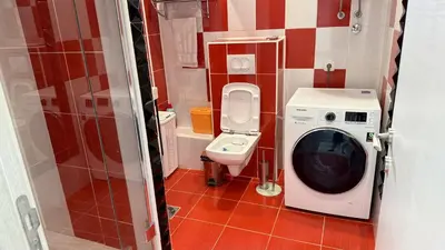 a small bathroom with a washing machine and a toilet at Guest House Victoria in Bar