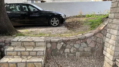 a black car parked next to a stone wall at Guest House Victoria in Bar