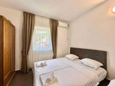 a bedroom with a bed with white sheets and a window at Hotel Lobo Budva in Budva