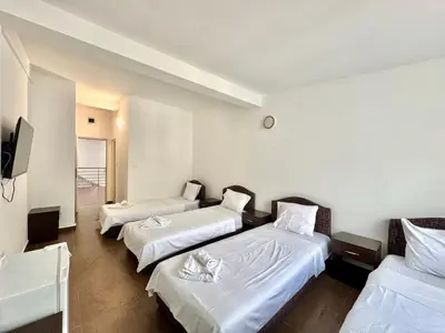 a hotel room with three beds and a television at Hotel Lobo Budva in Budva