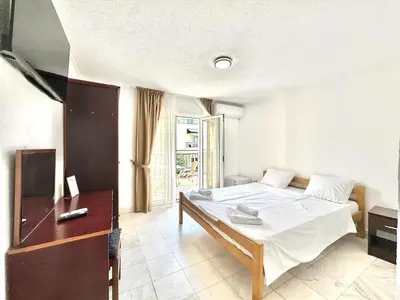 a bedroom with a bed and a desk and a window at Hotel Lobo Budva in Budva