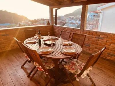 a wooden table with chairs and wine glasses on a balcony at Apartment Lamer in Petrovac na Moru