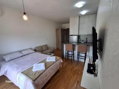a bedroom with a large bed and a kitchen at Ventura lux in Podgorica