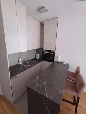 a kitchen with white cabinets and a black counter top at Ventura lux in Podgorica