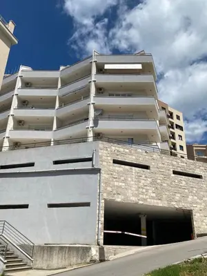 an apartment building with a parking garage in front of it at Blue Horizon Apartment in Becici in Budva