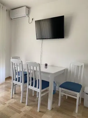 a white table with three chairs and a television on a wall at Blue Horizon Apartment in Becici in Budva