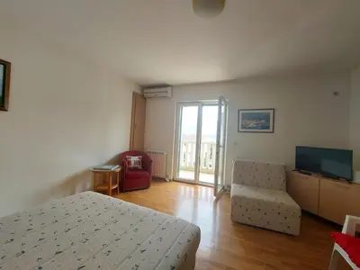 a bedroom with a bed and a television and a chair at Villa Lara Budva in Budva