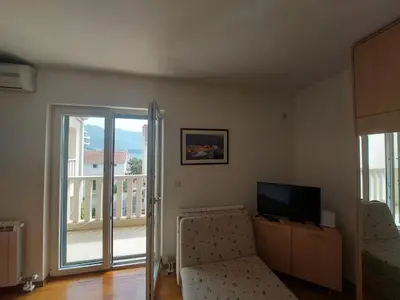 a living room with a couch and a television and a balcony at Villa Lara Budva in Budva