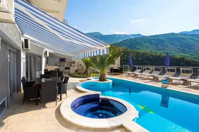 a swimming pool with a table and chairs next to a house at Montelux Apartments in Budva
