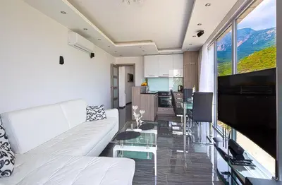 a living room with white furniture and a large window at Montelux Apartments in Budva