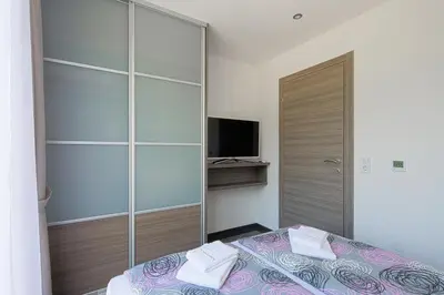 a bedroom with a bed and a closet with a television at Montelux Apartments in Budva