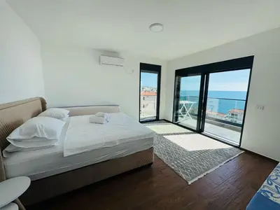 a bedroom with a bed and a view of the ocean at Swiss DELUXE Appartement in Dobra Voda