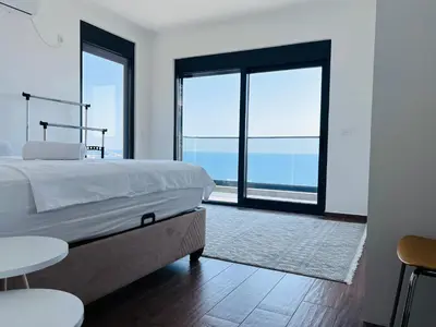 a bedroom with a bed and a view of the ocean at Swiss DELUXE Appartement in Dobra Voda