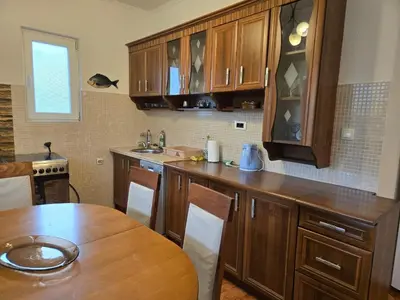 a kitchen with wooden cabinets and a wooden table at Apartment Anna in Polje
