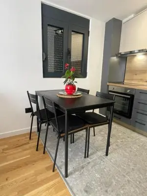 a black dining room table with chairs and a vase of flowers on it at Apartment Tara in Podgorica