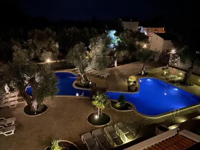 a swimming pool at night with chairs and trees at Villa Ponta in Buljarica