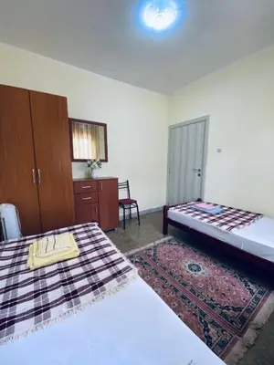 a bedroom with two beds and a cabinet and a rug at Guest house in Sutomore