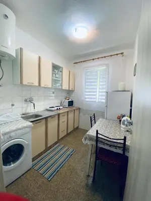 a kitchen with a table and a washing machine at Guest house in Sutomore