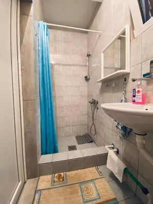 a bathroom with a shower with a blue shower curtain at Guest house in Sutomore
