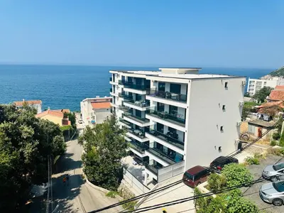 a white apartment building next to the ocean at Mellas Premium Apartment in Dobra Voda