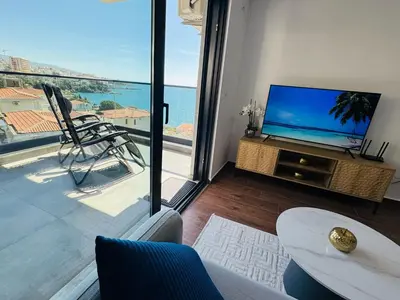 a living room with a tv and a view of the ocean at Mellas Premium Apartment in Dobra Voda