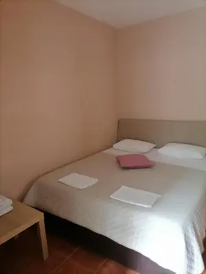 a bedroom with a bed with two sheets and a table at Apartments Ant in Budva