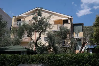 an apartment building with trees in front of it at Kuca Radovic in Petrovac na Moru