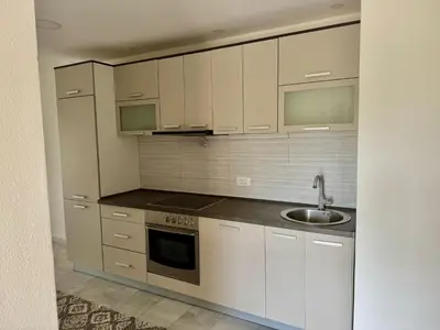 a kitchen with white cabinets and a sink at Valentina Apartman in Radanovići