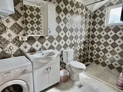 a bathroom with a toilet and a sink and a washing machine at Valentina Apartman in Radanovići