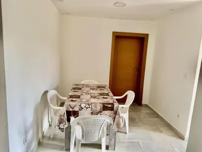 a dining room table with white chairs and a table cloth at Valentina Apartman in Radanovići