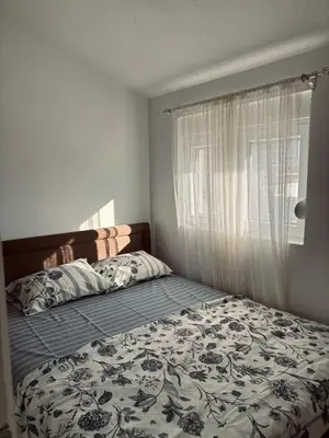 a bedroom with a bed with a floral comforter and a window at My big house in Kotor