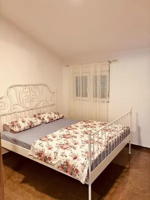 a bedroom with a white bed with a floral bedspread at My big house in Kotor
