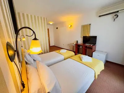 a hotel room with two beds and a desk at Central Hotel & Restaurant in Budva