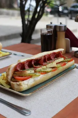 a sandwich on a plate on a table with a drink at Central Hotel & Restaurant in Budva