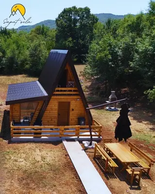 a log cabin with a solar roof and a picnic table at Wooden House Šapat sela in Podgorica