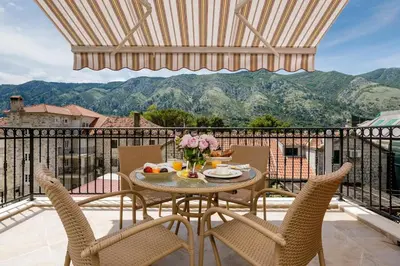 a table with a vase of flowers on a balcony at Apartment Noel Kotor Dobrota in Kotor