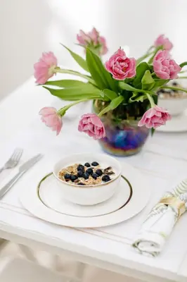 a table with a bowl of blueberries and a vase of pink flowers at Apartment Noel Kotor Dobrota in Kotor