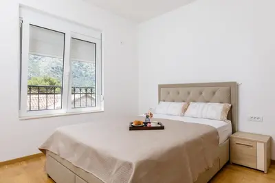 a bedroom with a bed and two windows at Apartment Noel Kotor Dobrota in Kotor