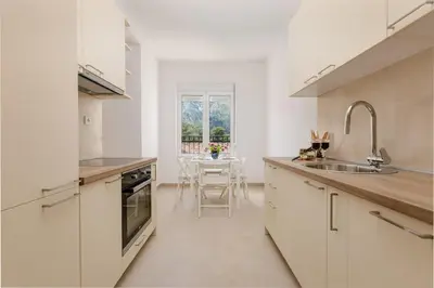 a white kitchen with a sink and a table at Apartment Noel Kotor Dobrota in Kotor