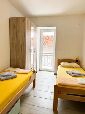 two beds in a room with a window at Apartman Zinzula in Petrovac na Moru