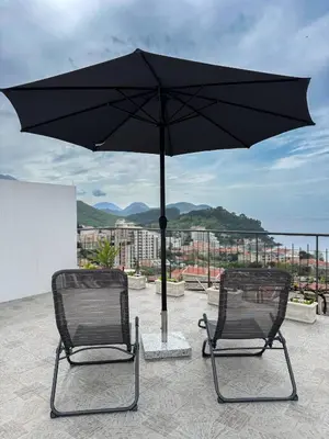 two chairs sitting under an umbrella on a roof at Apartman Zinzula in Petrovac na Moru