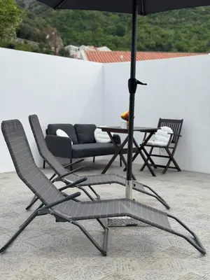 a pair of chairs and an umbrella on a patio at Apartman Zinzula in Petrovac na Moru