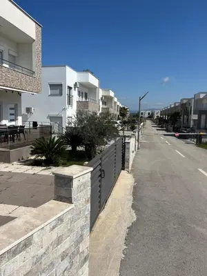 an empty street with white houses and a fence at Vila Dior Donji Stoj in Donji Štoj