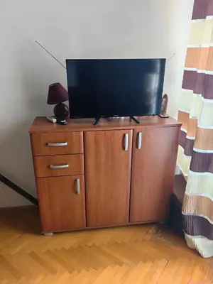a flat screen tv on top of a wooden cabinet at Small duplex near beach in Sutomore
